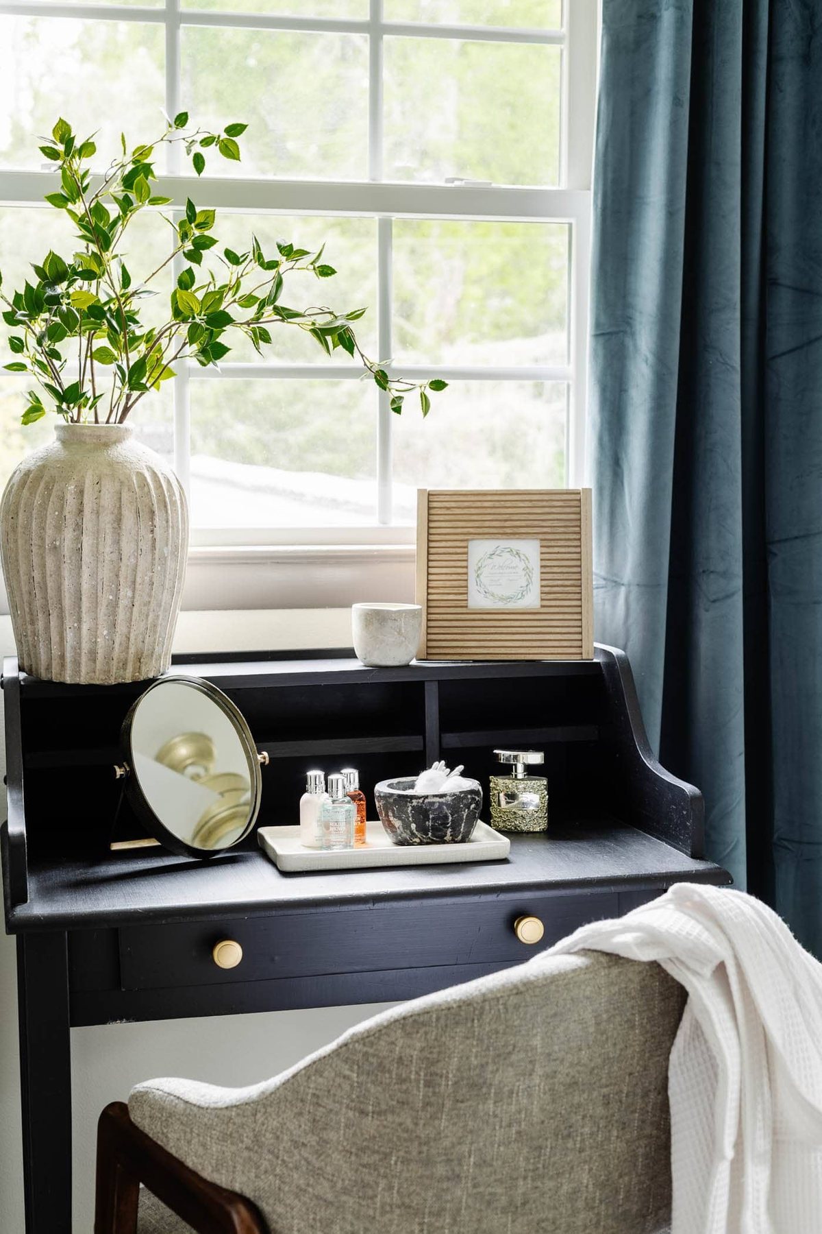 painted black vanity with gold drawer knobs in front of a window