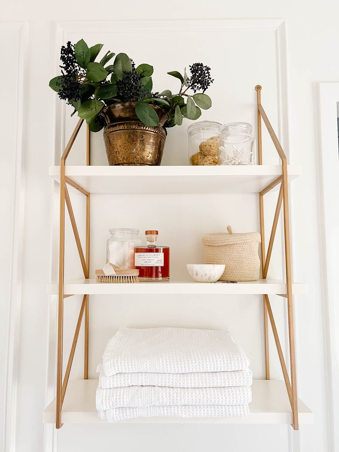 open shelving in a bathroom with apothecary jars and waffle weave towels