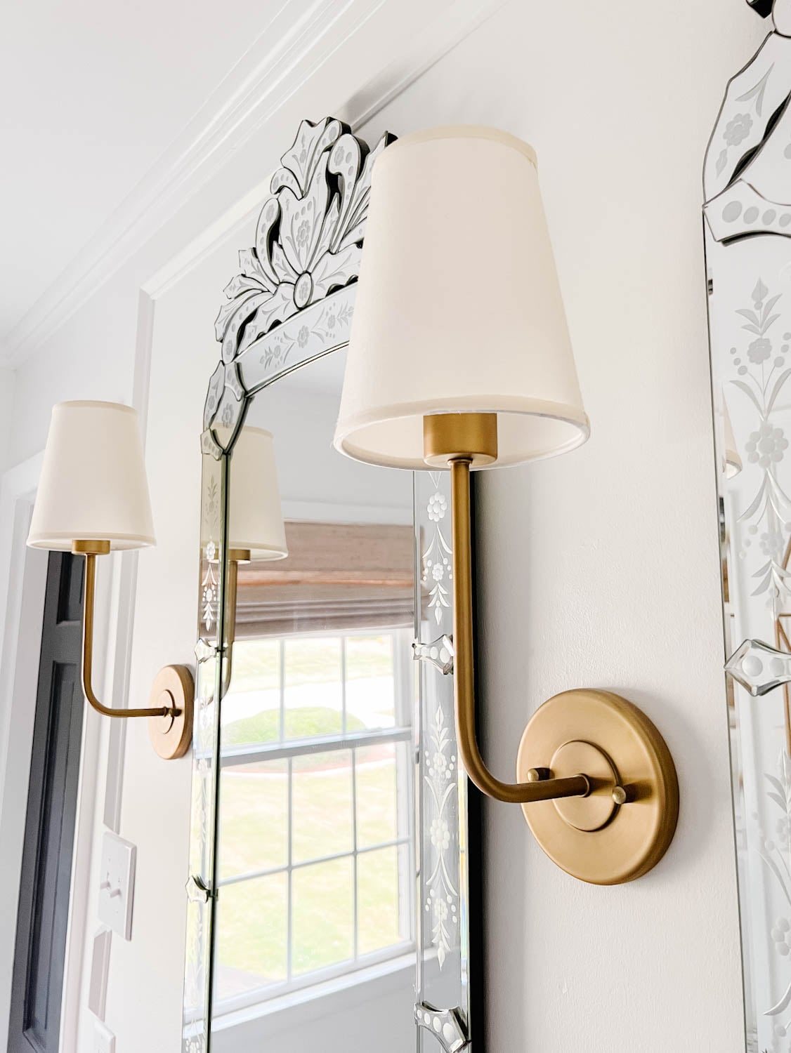 vintage wall sconces on either side of Venetian mirrors in a bathroom