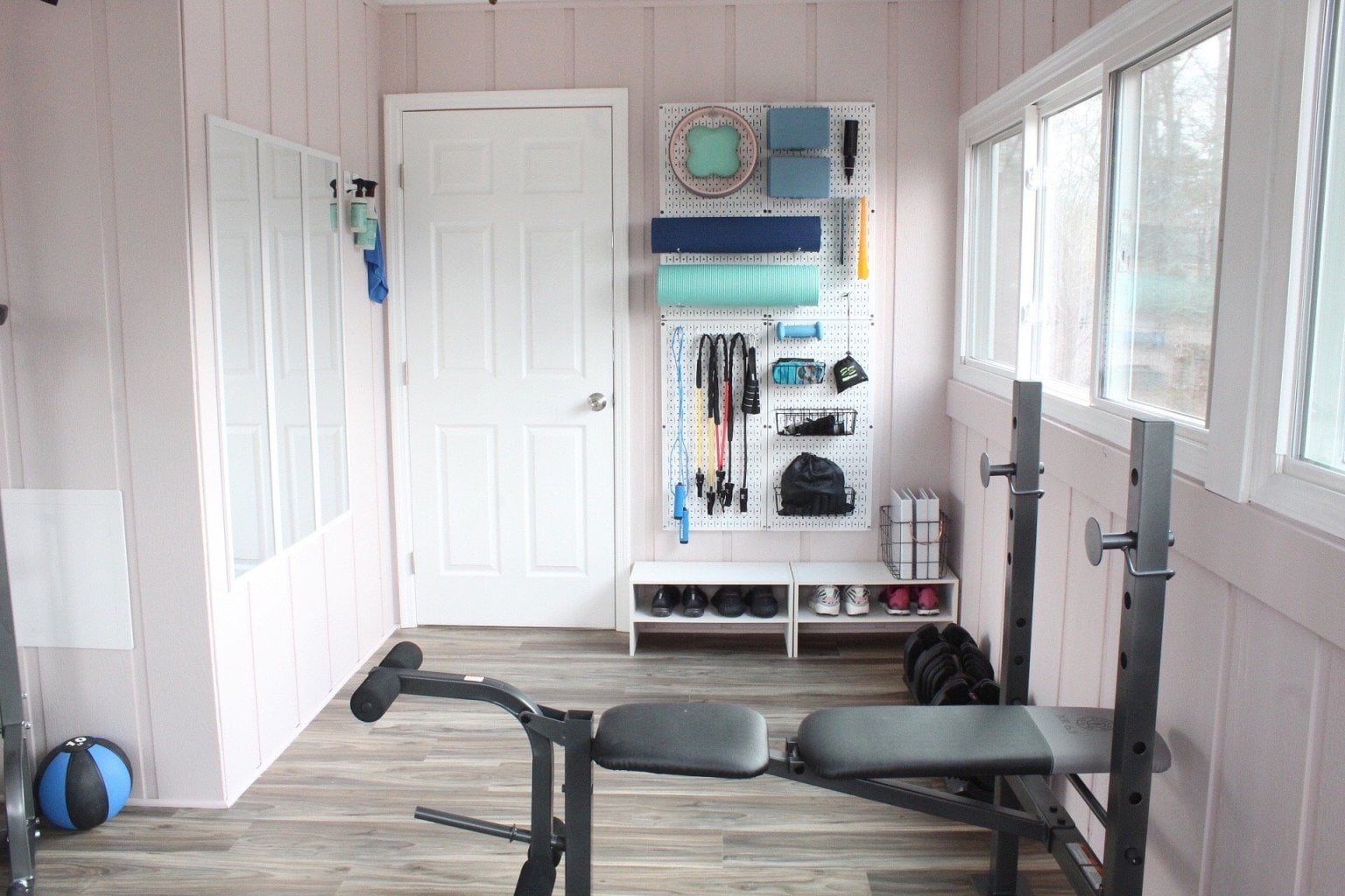 workout room with wall organizer pegboard for small workout equipment