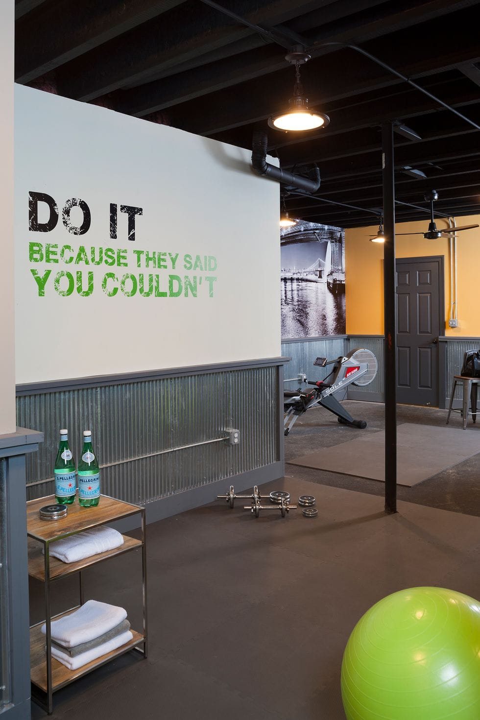 home gym with shelf, industrial lighting, and wall quote mural