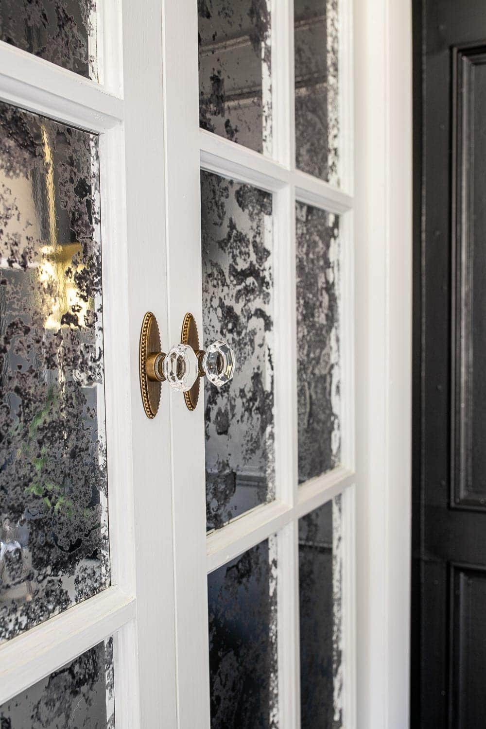 white bifold French doors with antique mirror film to cover glass and crystal door knobs