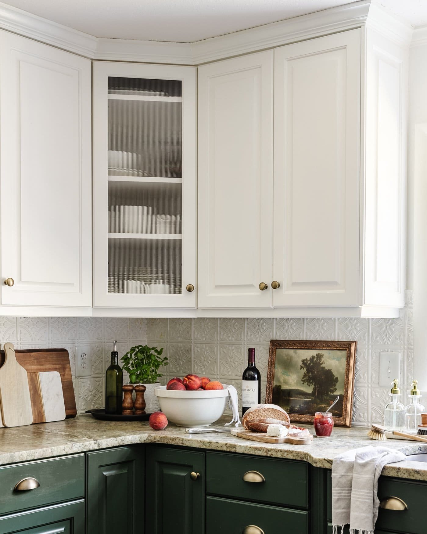 reeded glass cabinet door using decorative window film in a kitchen with bowl of peaches, tray, and vintage art