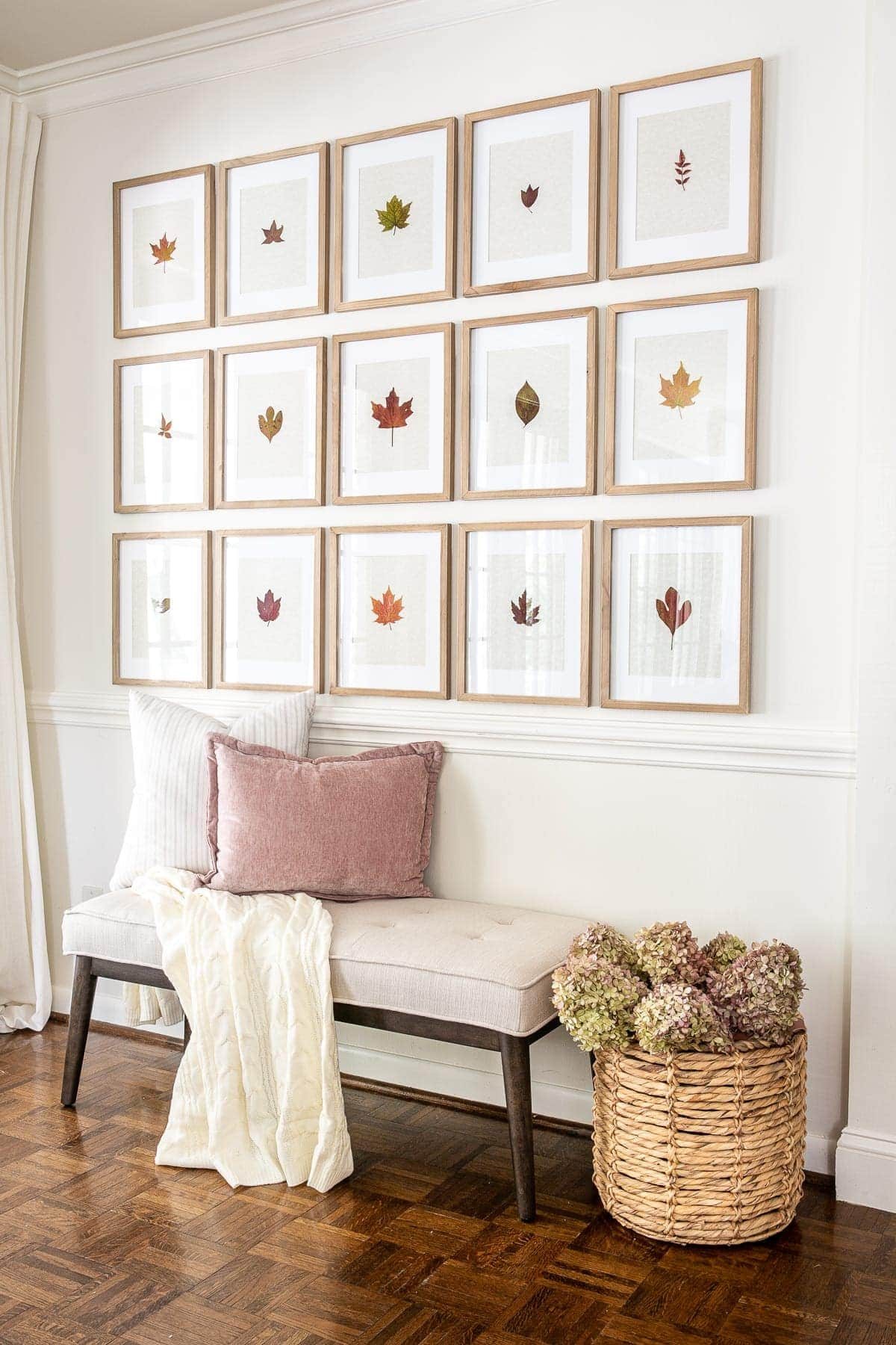fall entryway using gallery wall with pressed leaves and dried hydrangeas in a basket beside a bench