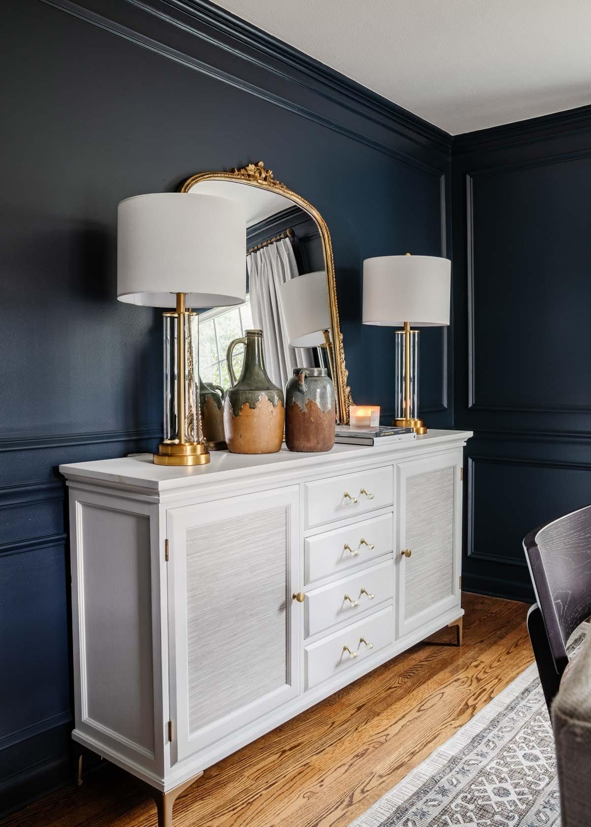 navy blue dining room with white sideboard and gilded mirror