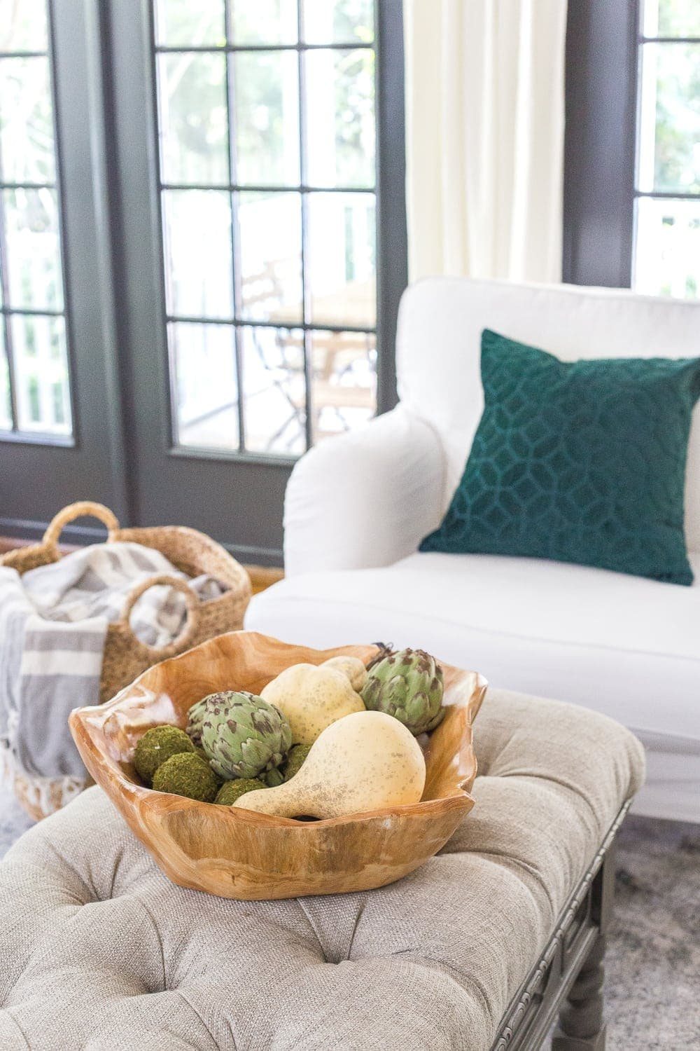 wooden bowl of gourds and artichokes on a living room coffee table