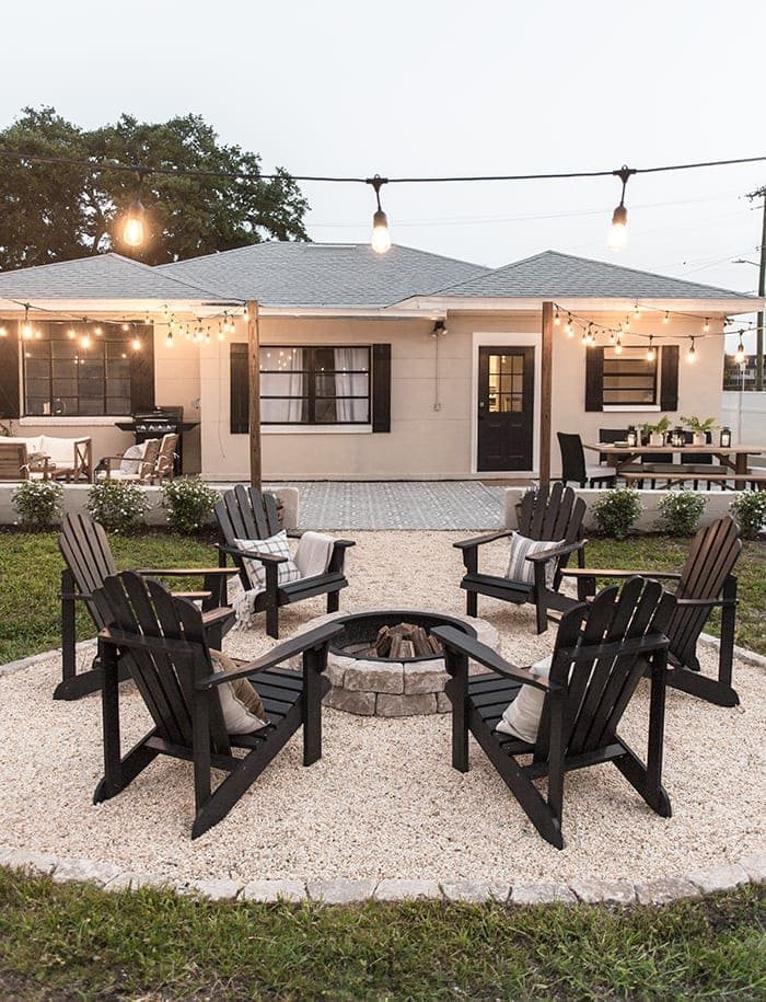 backyard fire pit with string lights and pea gravel
