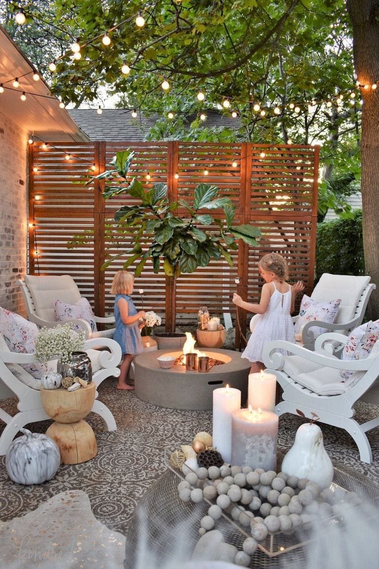 dreamy fire pit with string lights, wood screen, and limewashed brick