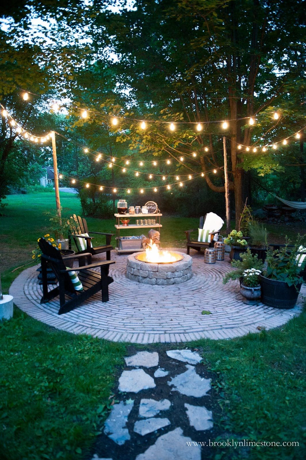 fire pit with string lights and stone walkway