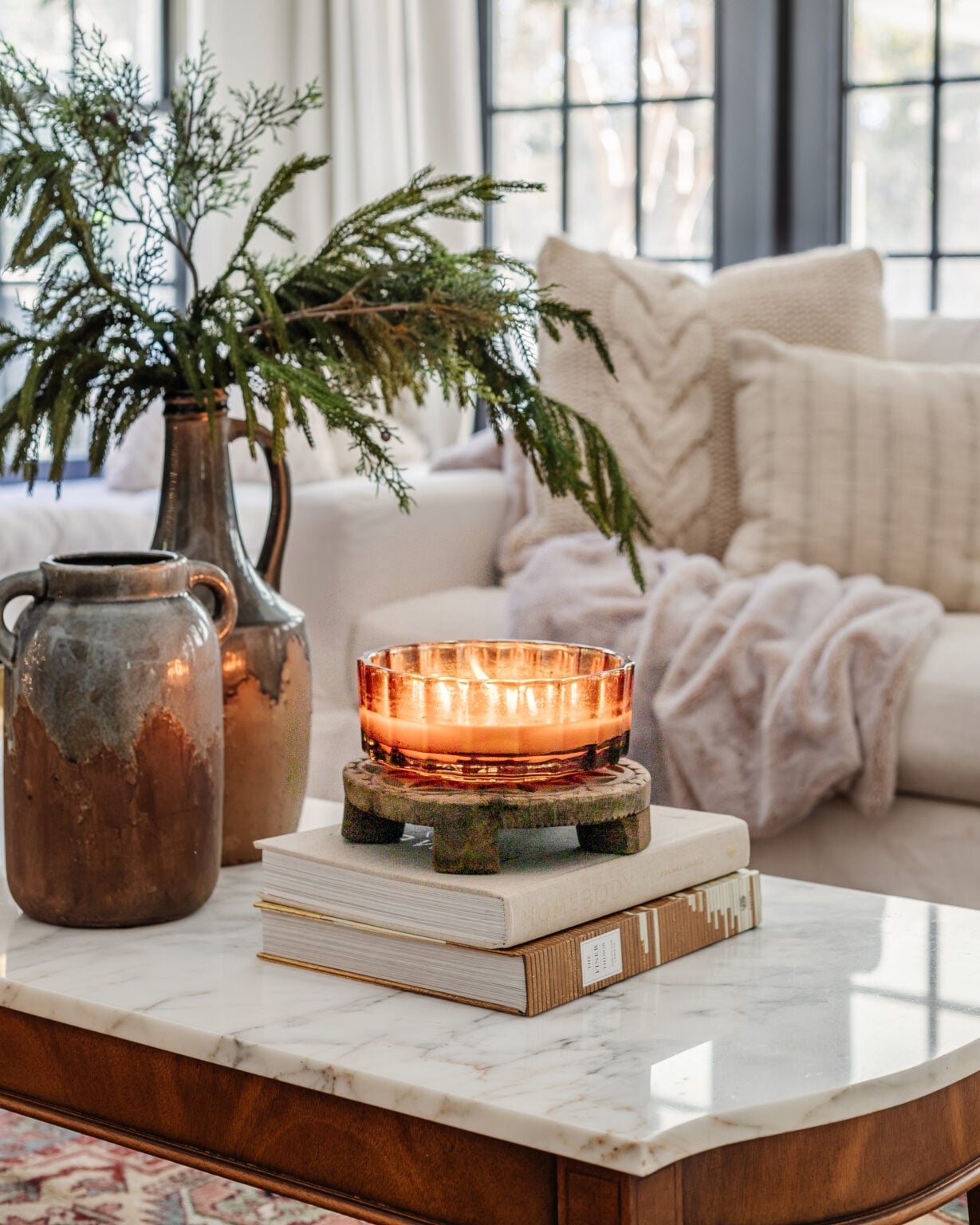 candle, books, and vase with winter branches on a coffee table for January decor