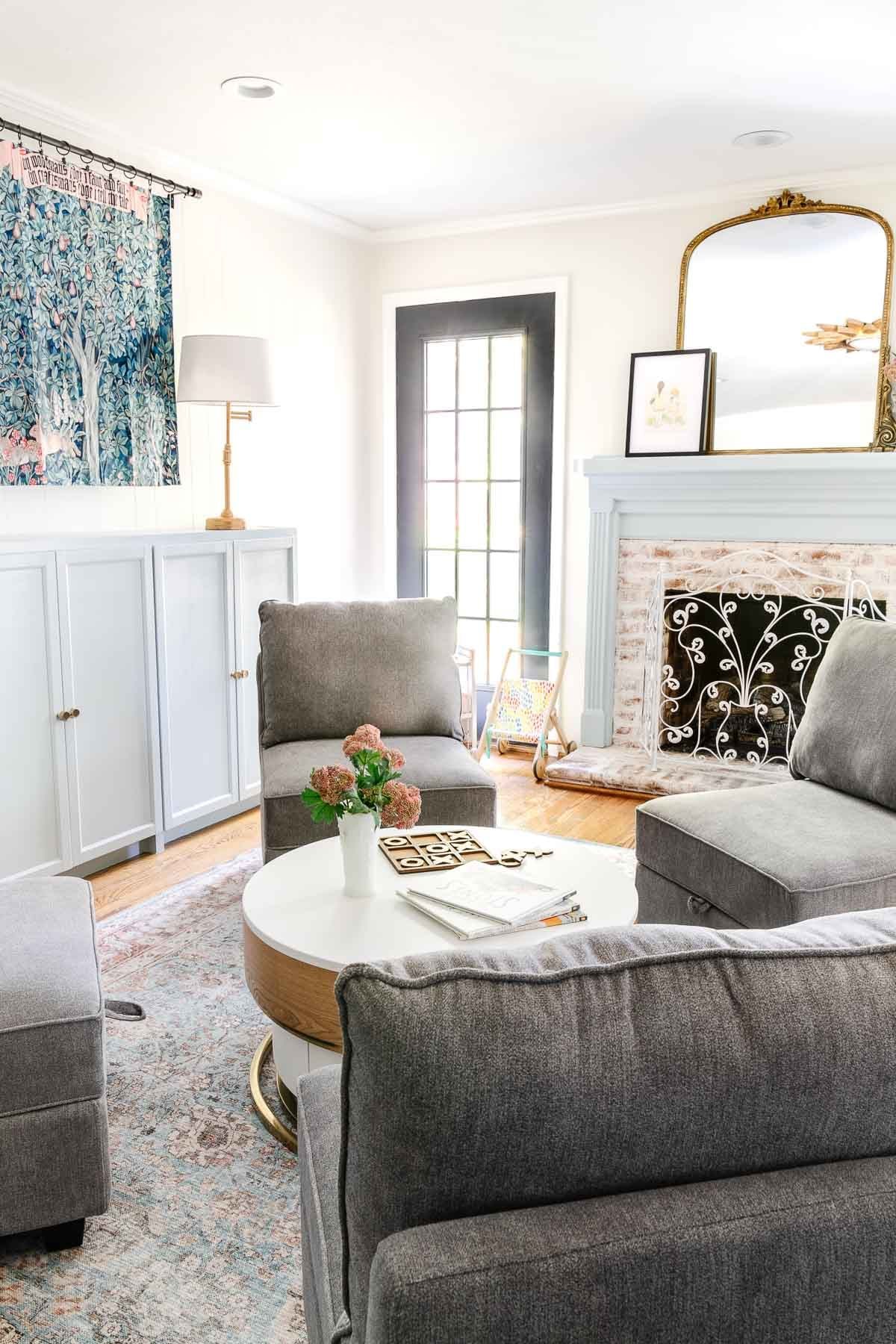white playroom with light blue mantel and toy storage cabinets, William Morris tapestry, and storage furniture