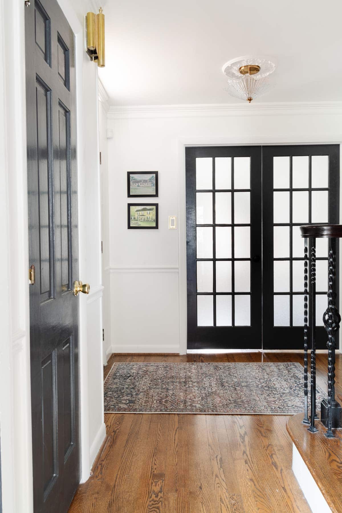 house portrait art beside front door in foyer with double French doors leading to home office