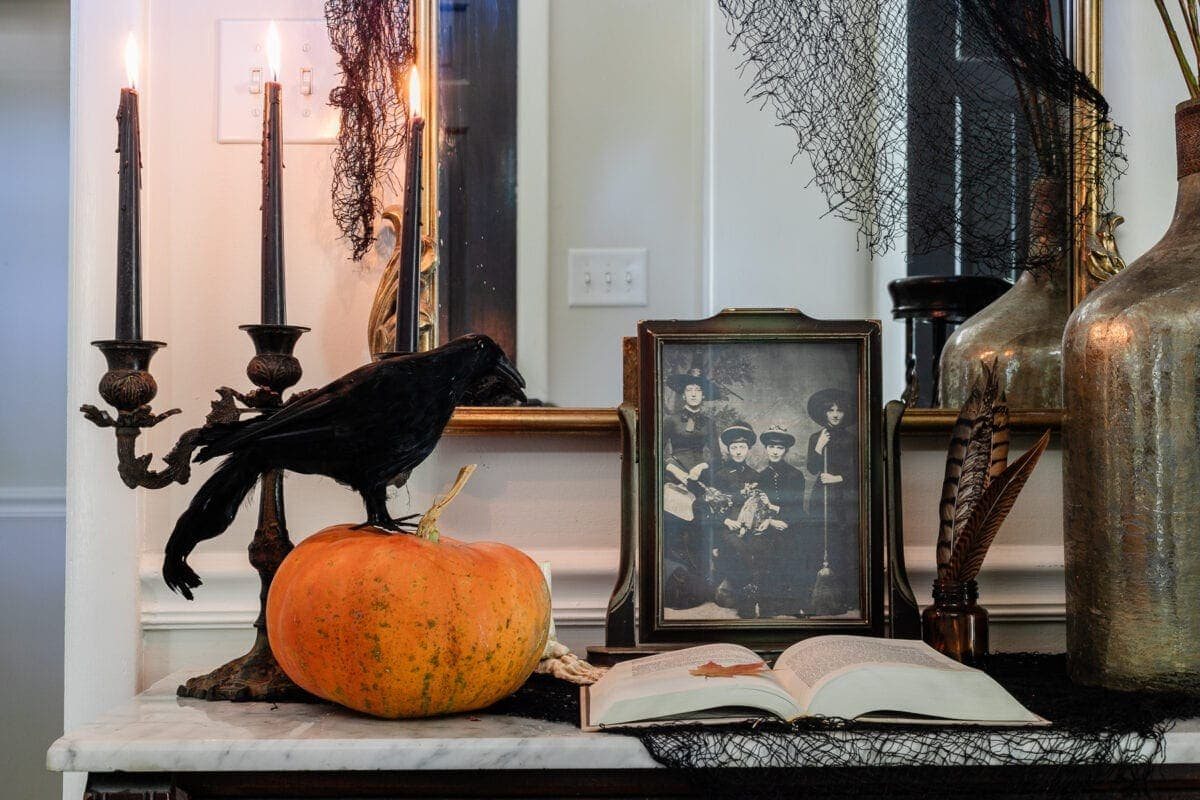 spooky table decor with pumpkin, raven, old witch portrait, and candelabra