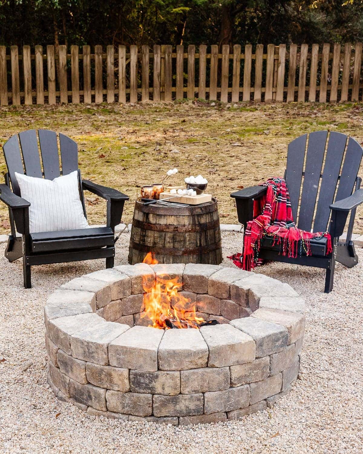 diy stone fire pit in a backyard with adirondack chairs