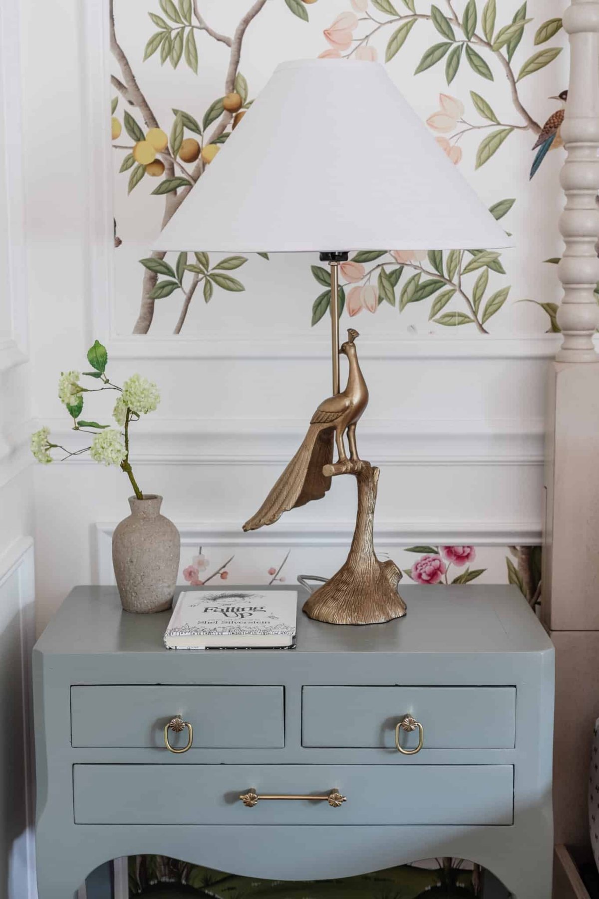 kids bedroom side table with animal lamp, vase of flowers, and book