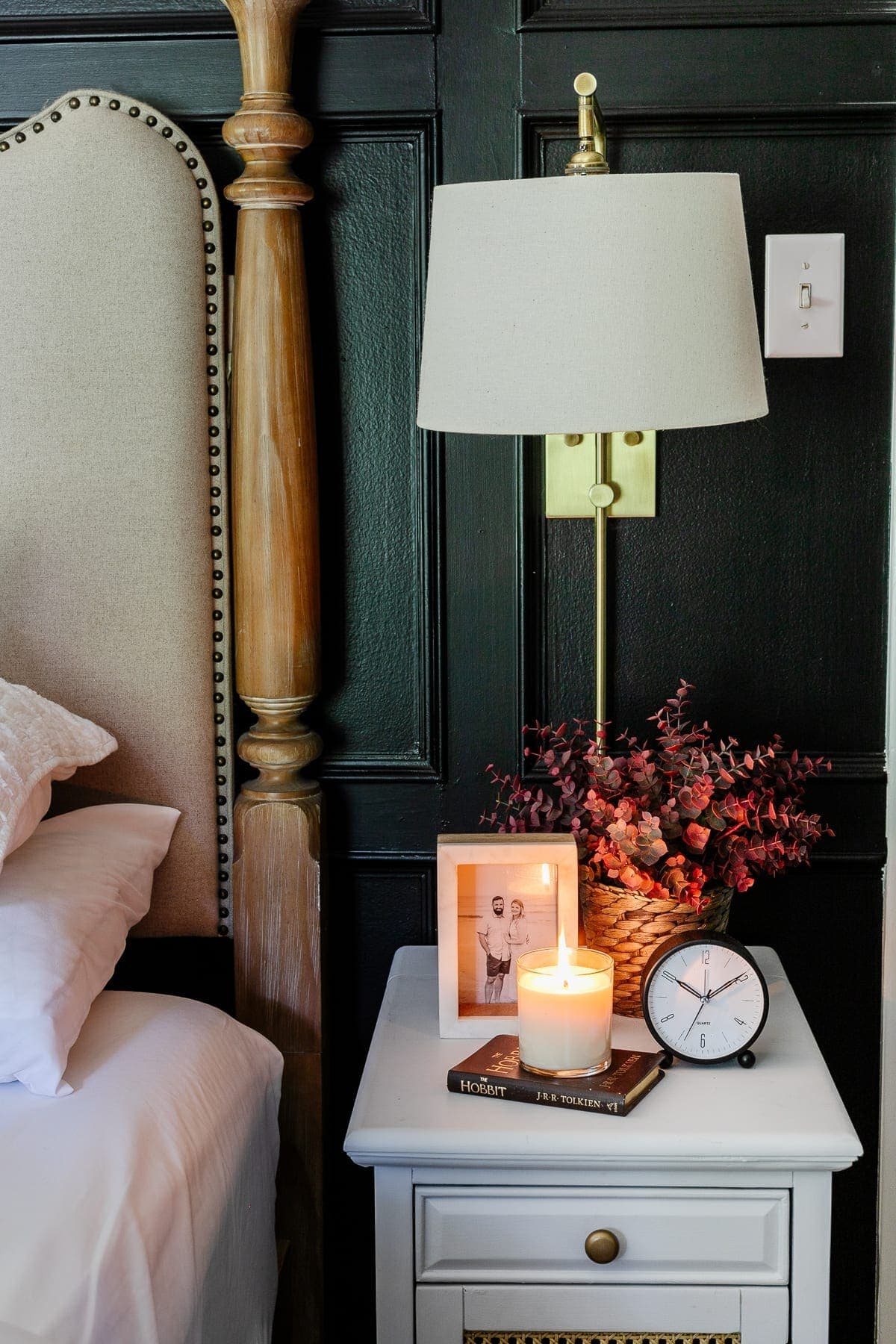 nightstand with fall decor featuring candle, clock, picture frame, book, and fall plant