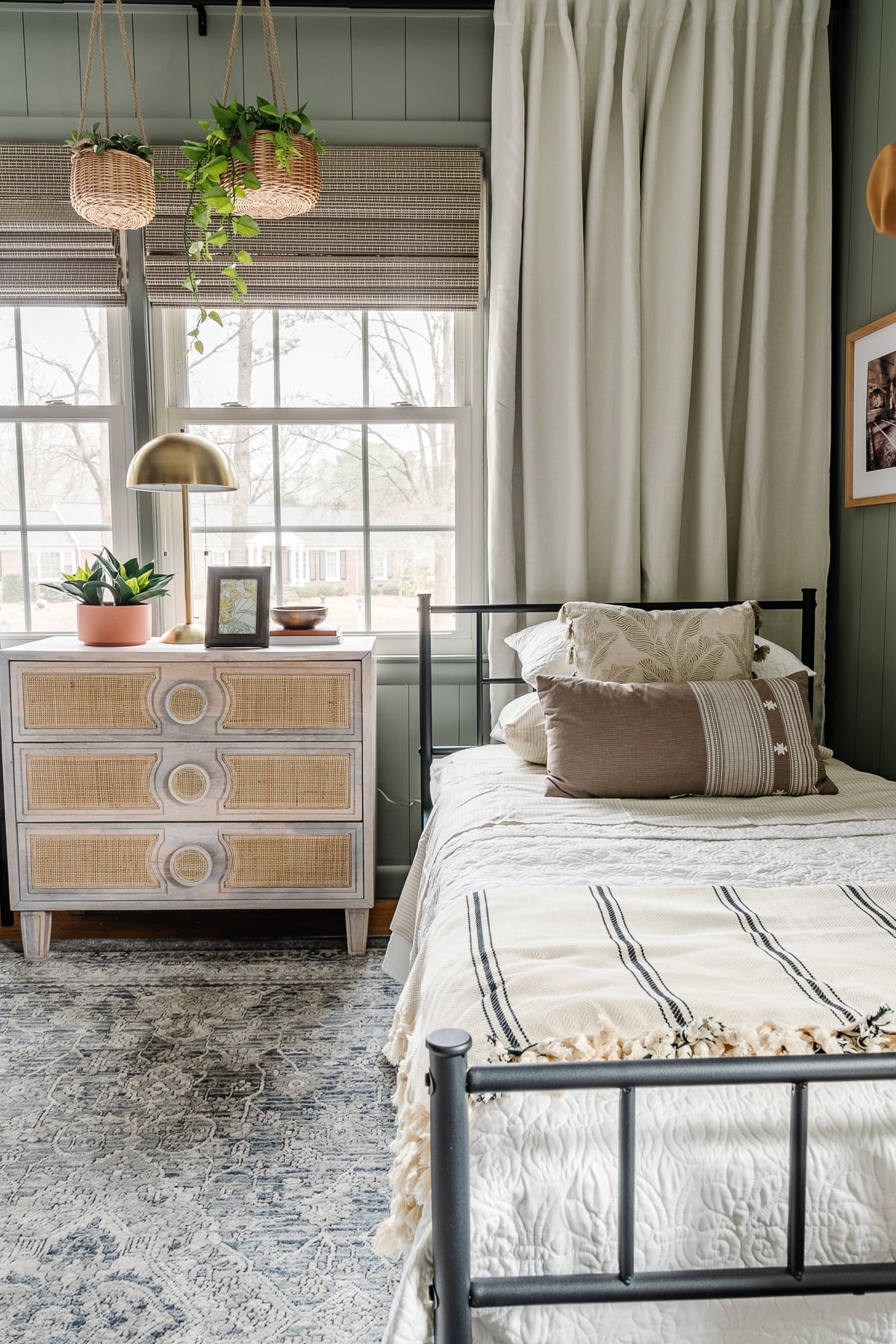 dresser nightstand beside twin bed with windows behind