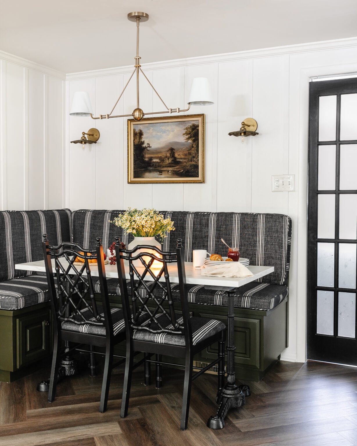 breakfast nook banquette with striped cushions, black bamboo chairs, and black French door