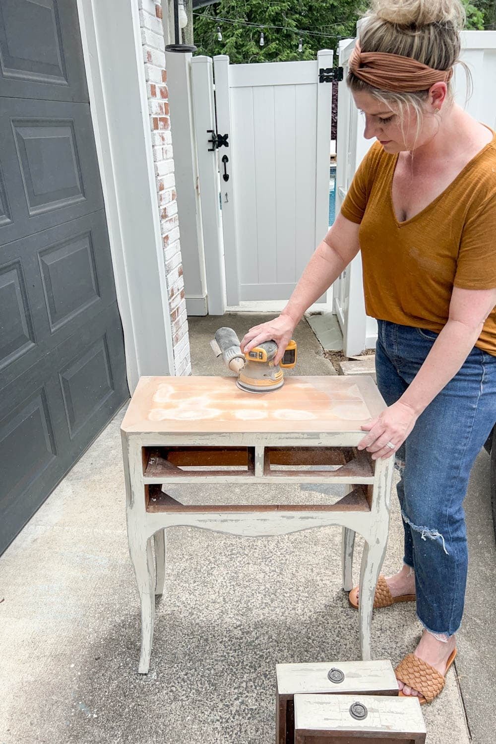 sanding a bedside table to remove distressed paint