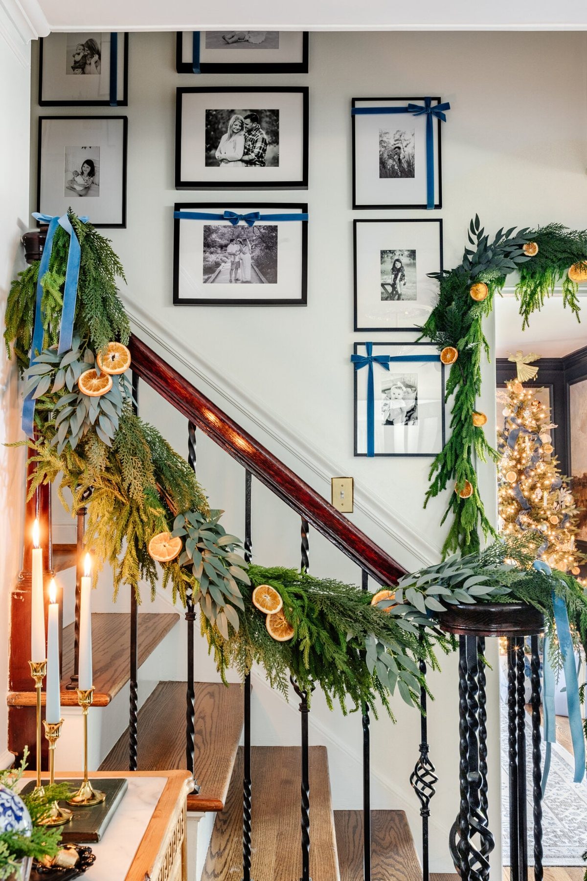family photo gallery wall with Christmas bows going up a staircase