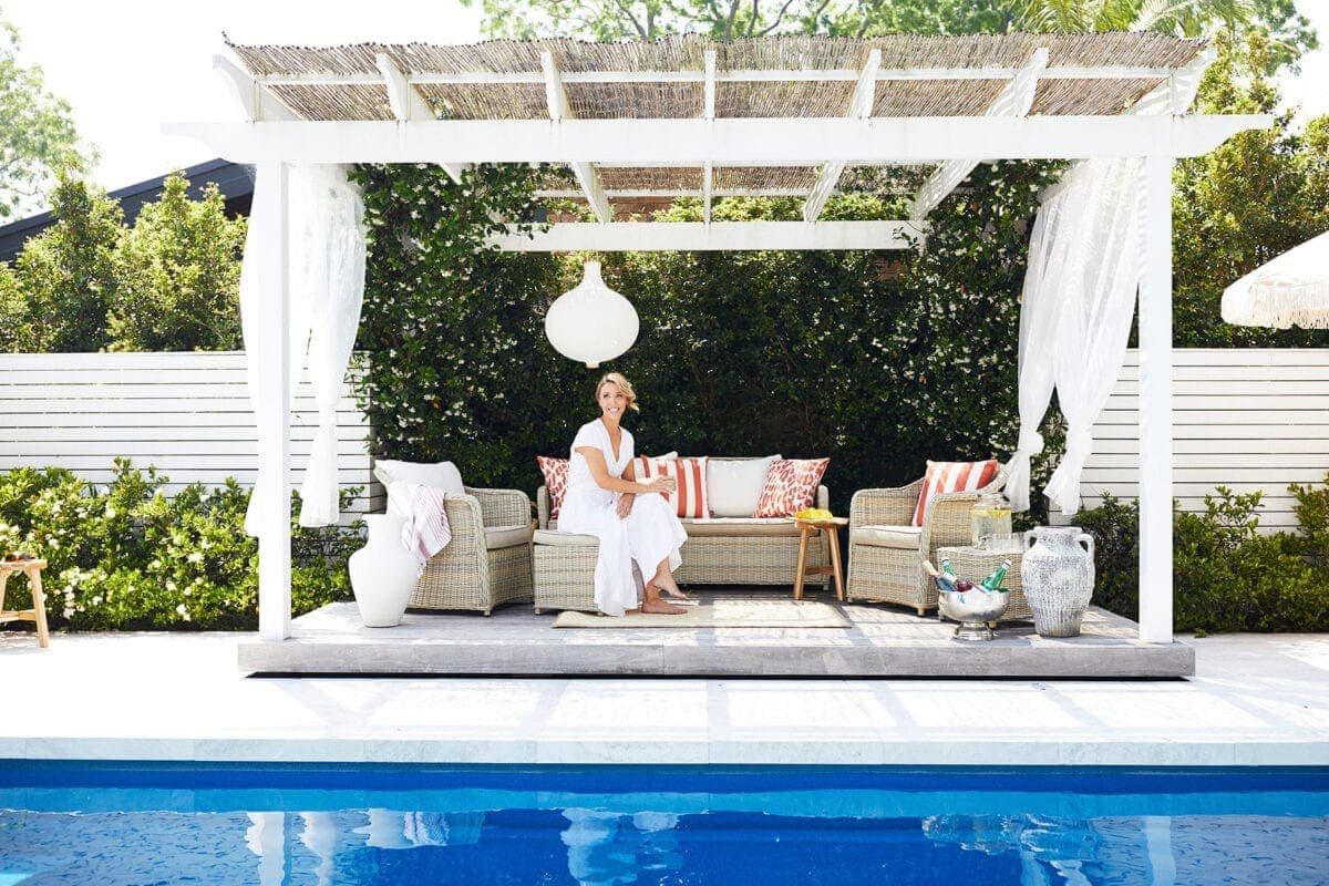 pool cabana with white gauze curtains and rattan outdoor furniture