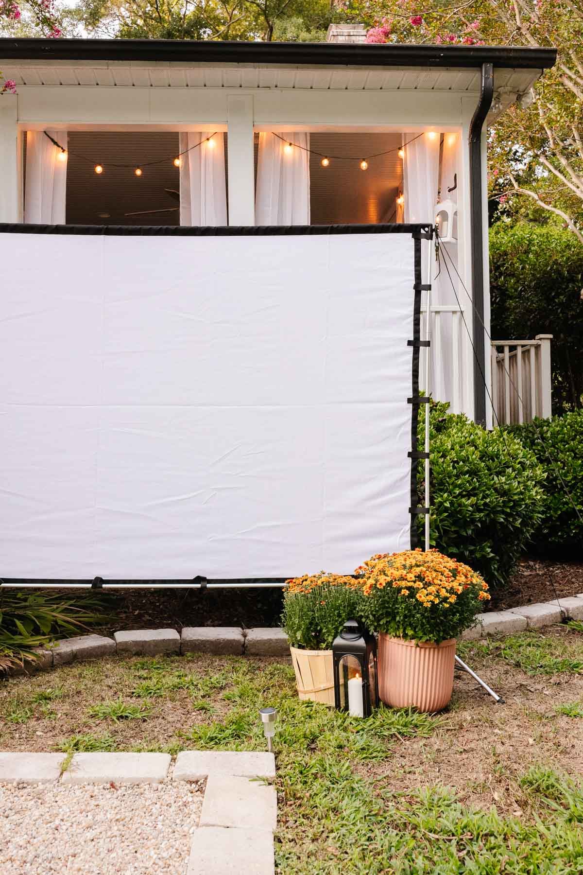 outdoor fall decor - garden mums and lanterns around outdoor movie screen for backyard party