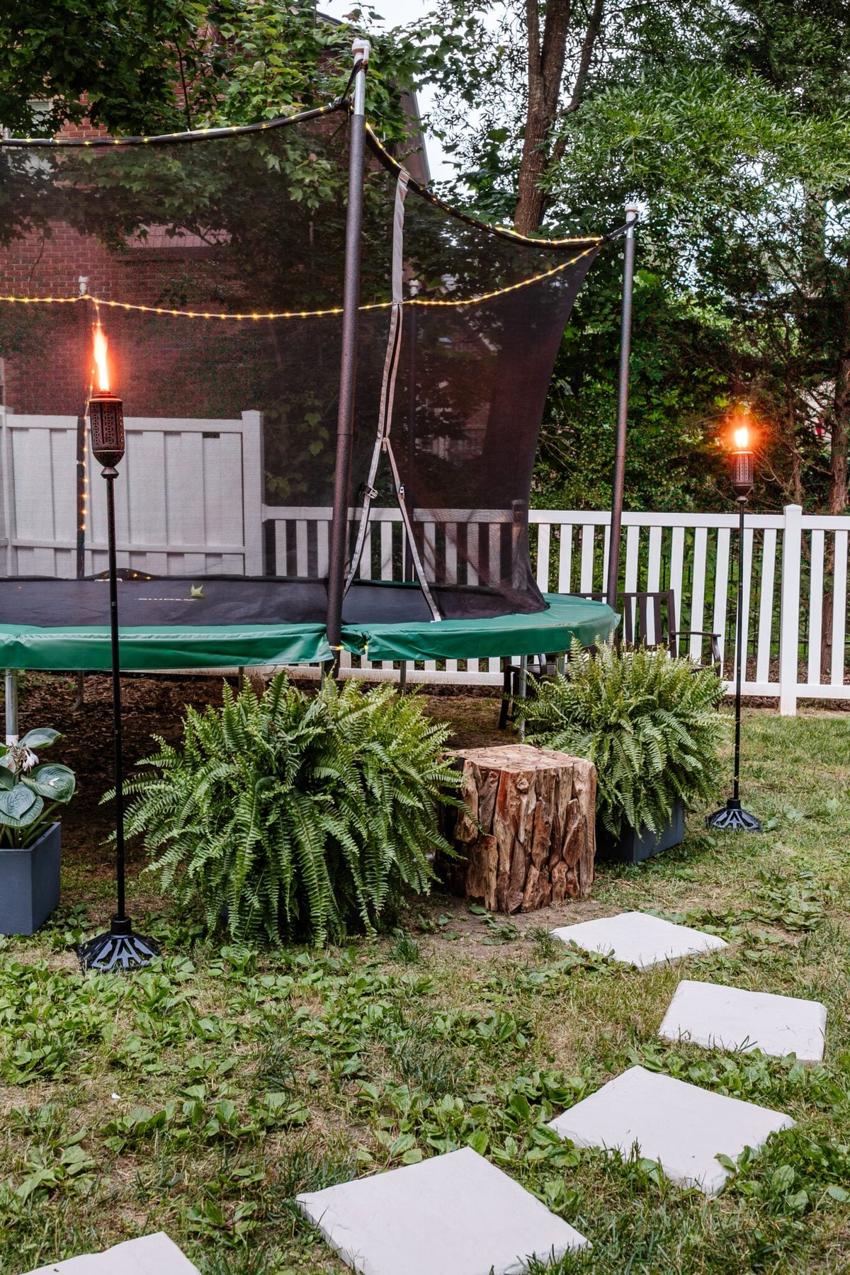 trampoline with tiki torches around it to repel mosquitoes in the yard