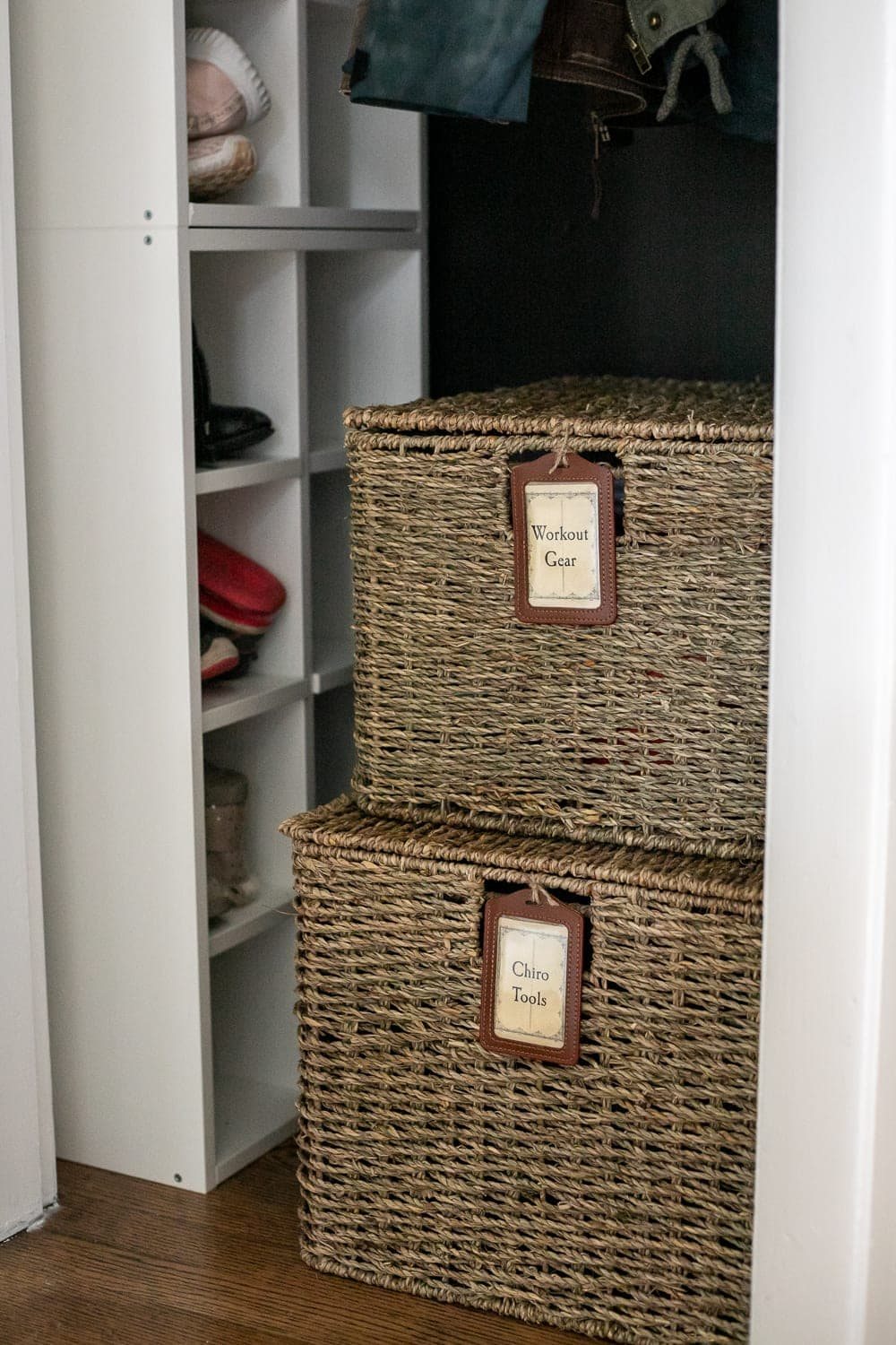 lidded baskets with labels in a coat closet for organizing workout gear