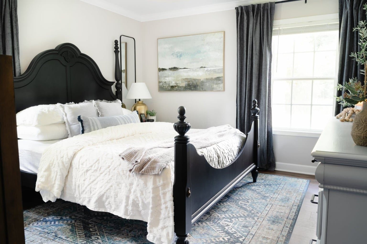 small primary bedroom with black poster bed and gray walls