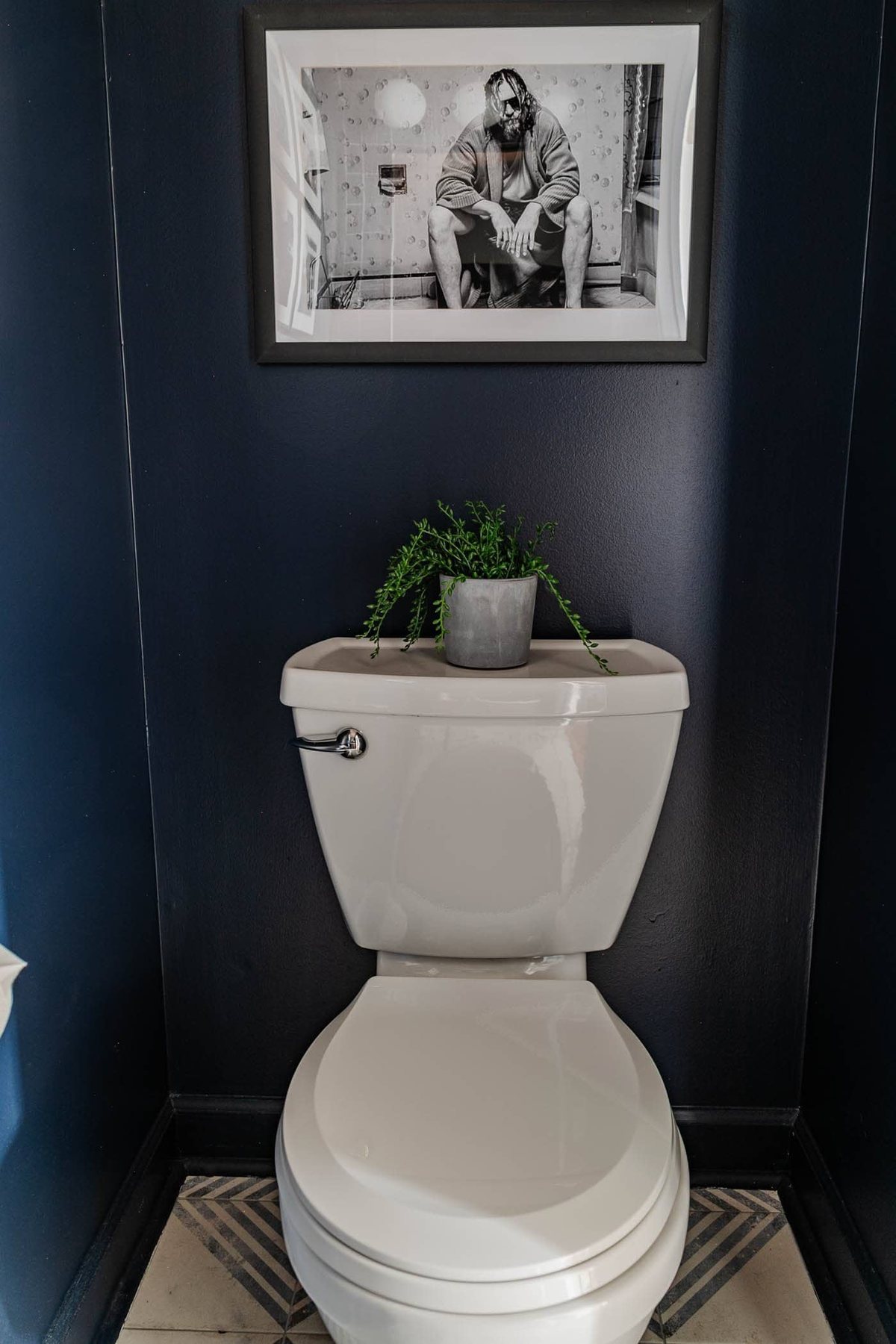 navy blue small powder room with The Big Lebowski art above toilet
