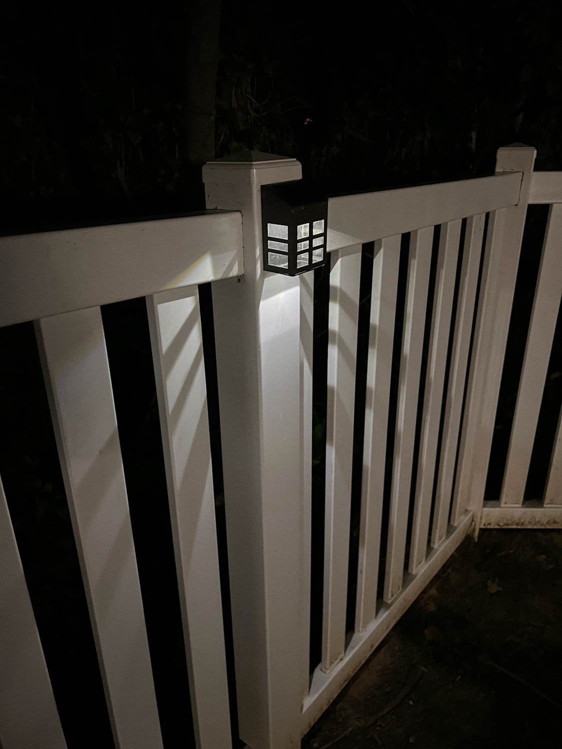a solar step light attached to a fence post lit up at night