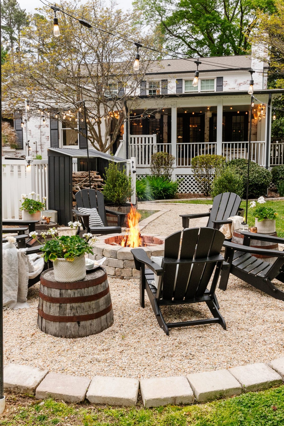 finished backyard fire pit after outdoor spring cleaning with potted plants, string lights, and pea gravel sitting area