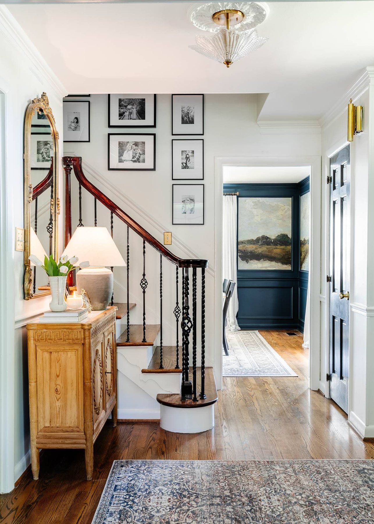 before and after foyer front entryway with white walls, hardwood floors, and carved wood cabinet