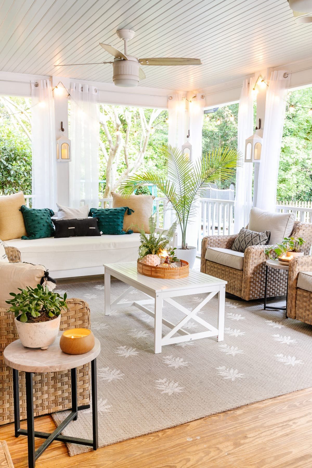 back porch after with mosquito net curtains, string lights, outdoor day bed, outdoor conversation set, and floral block outdoor rug