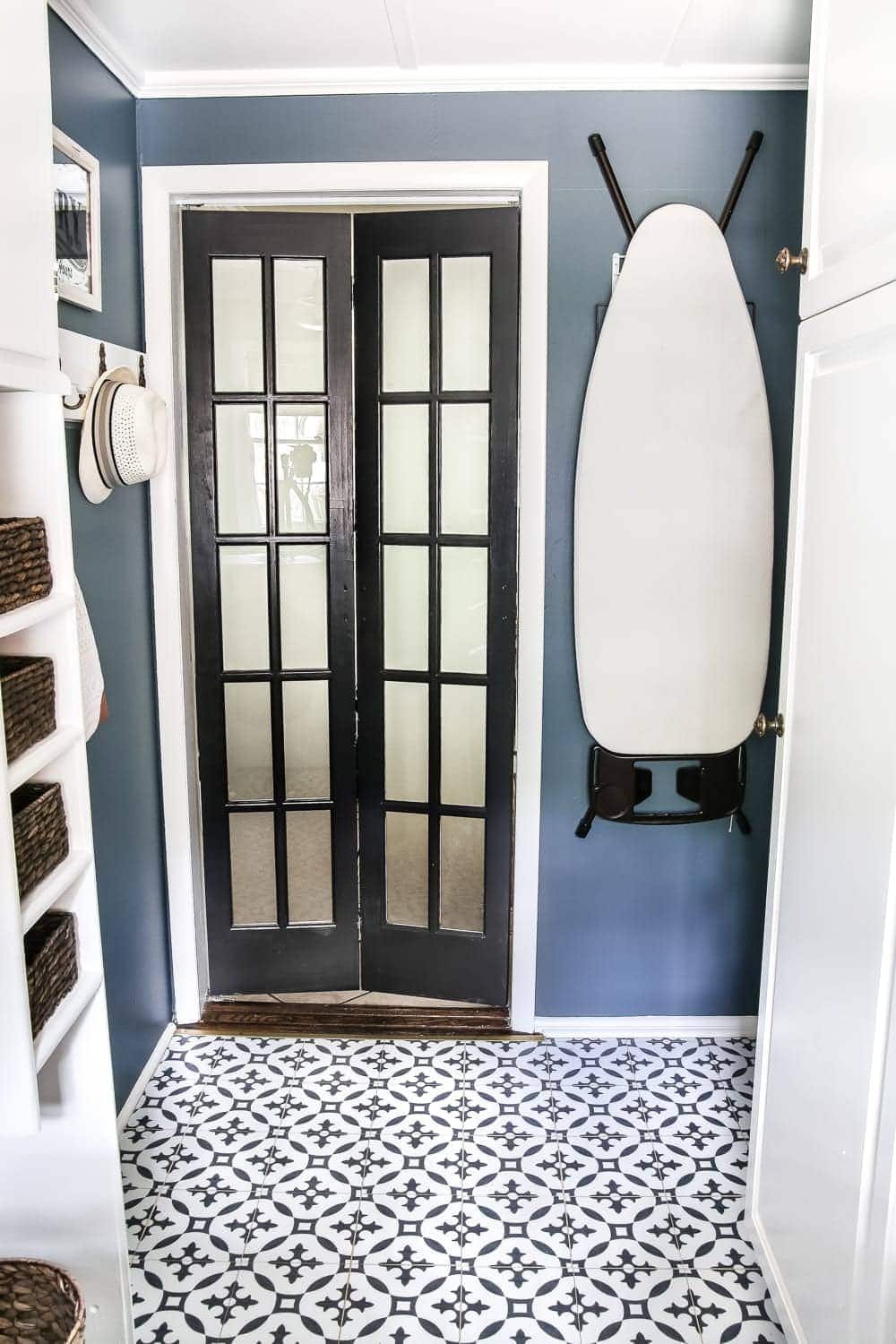 navy blue laundry room with black and white moroccan peel and stick tile floors and black bifold French door