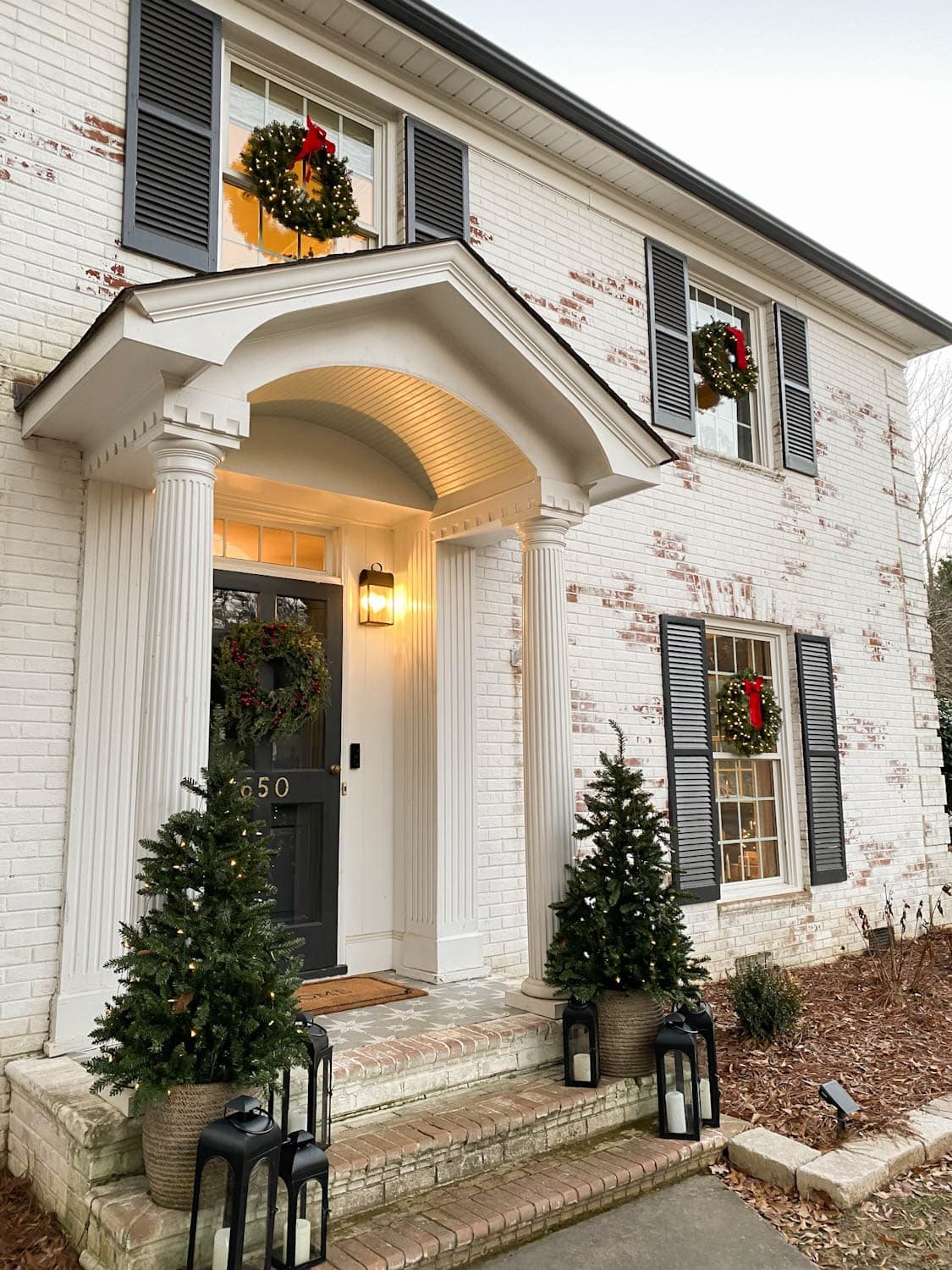 pre-lit Christmas wreaths on exterior windows of house