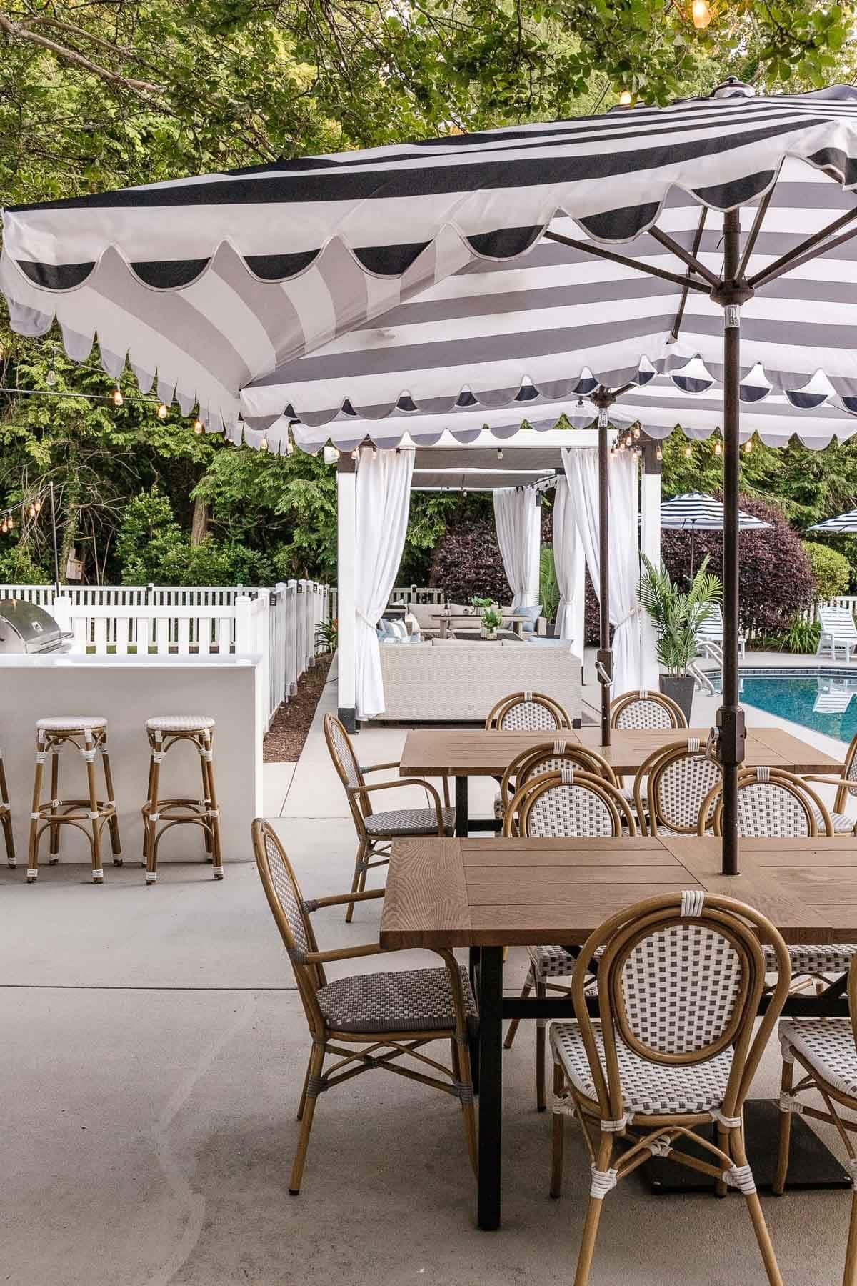outdoor dining tables and chairs on a patio with cabana umbrellas