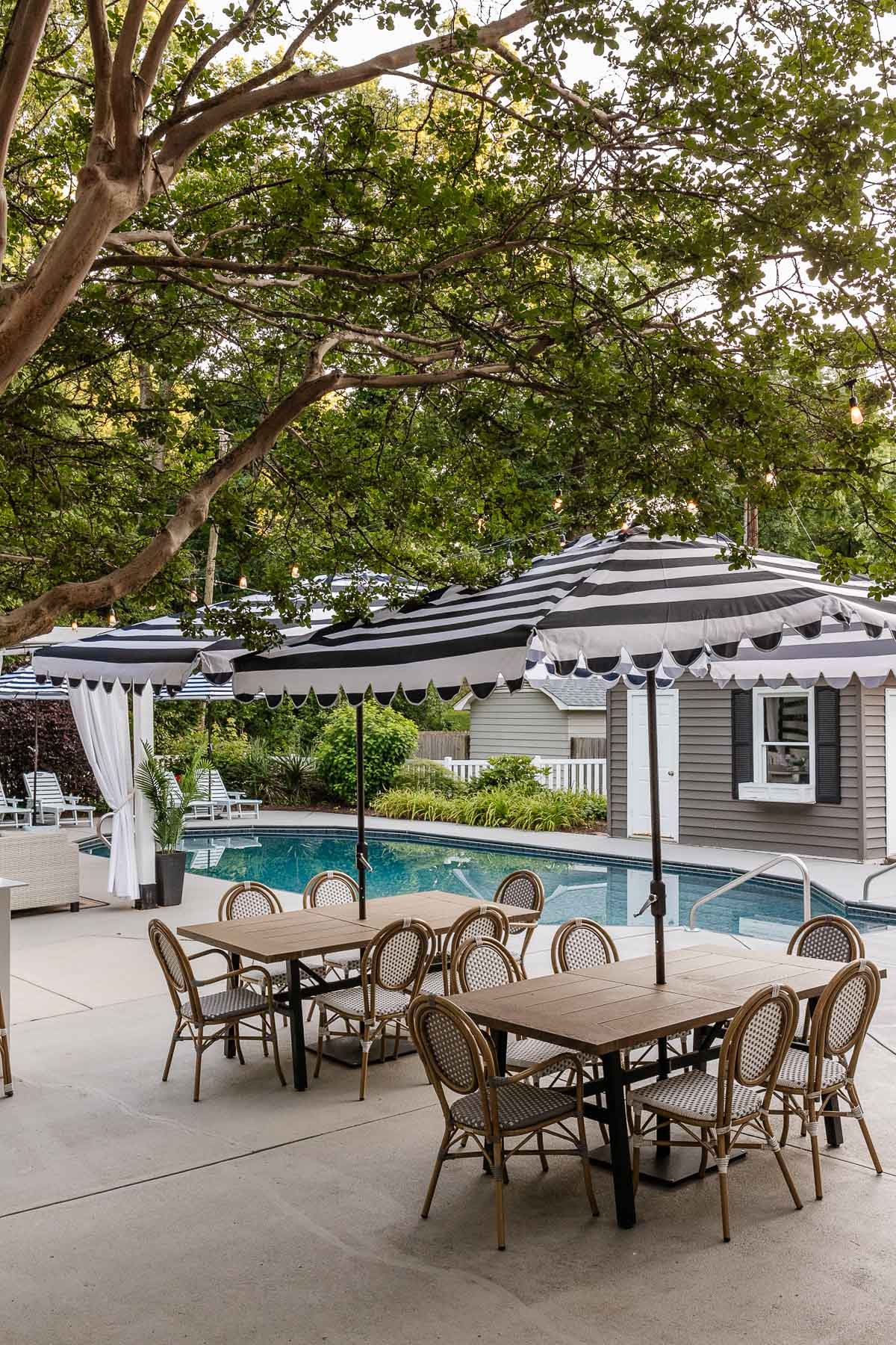 outdoor dining tables and chairs on a patio with cabana umbrellas