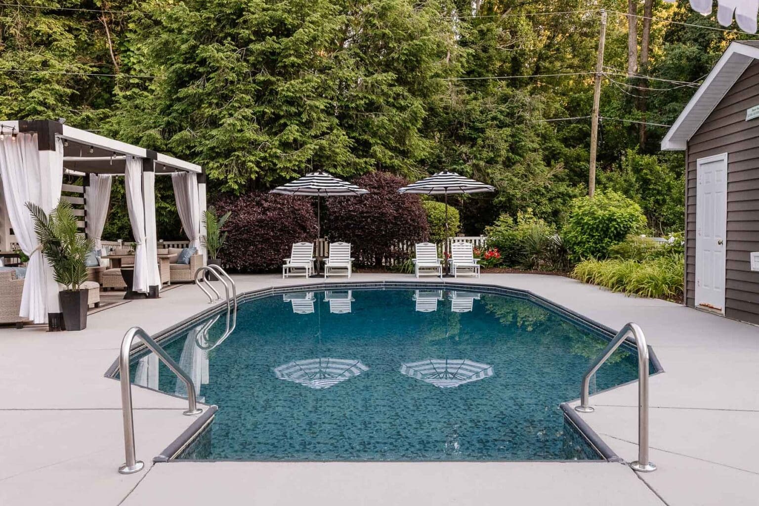 backyard pool with lounge chairs and umbrellas and diy cabana