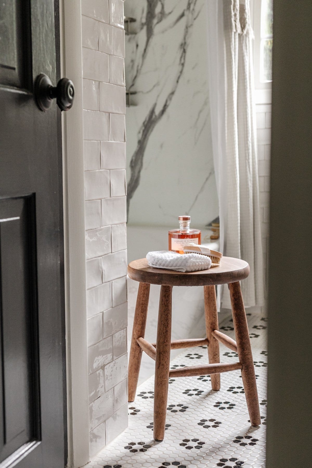bathroom stool with toiletries and black and white bathroom tile