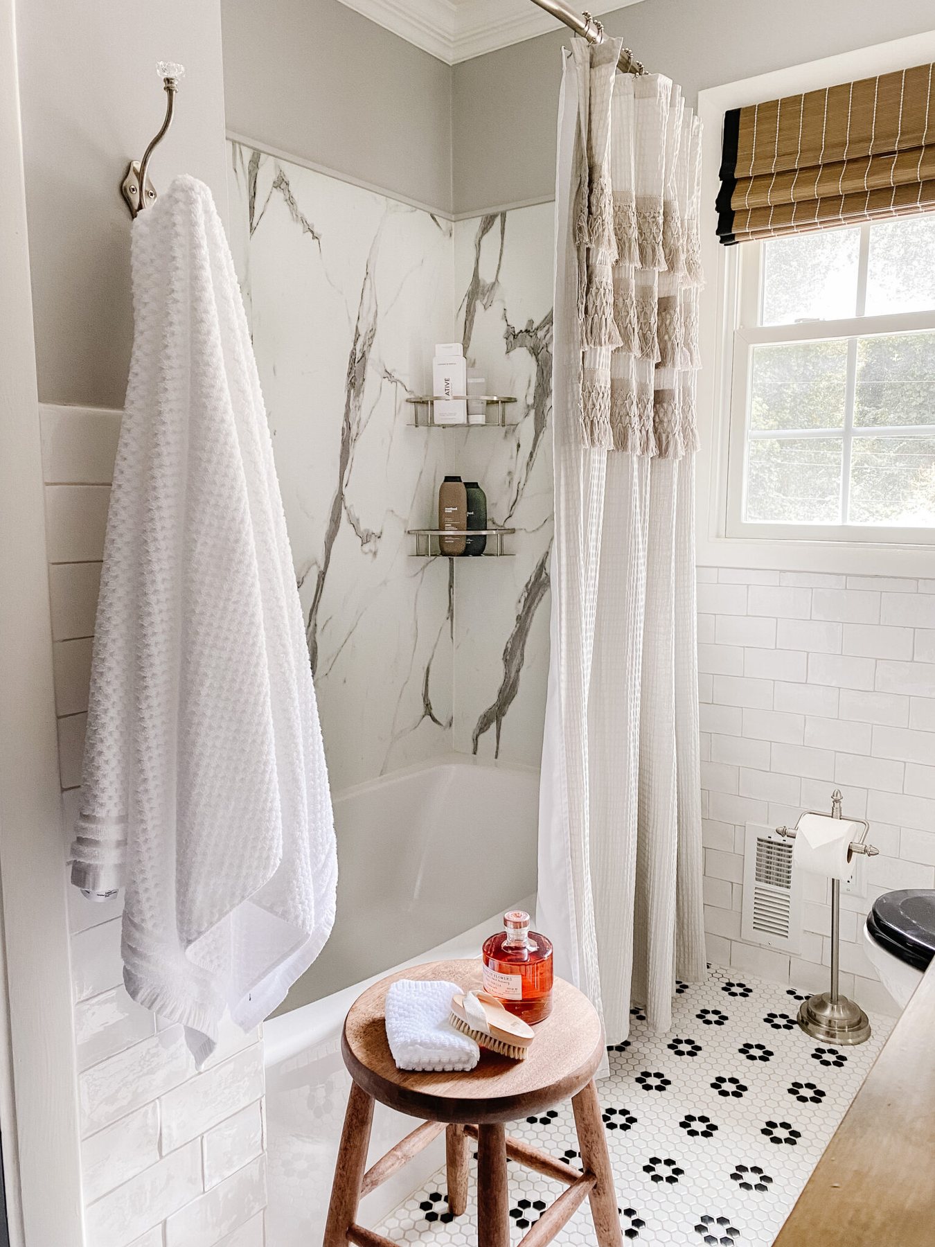 marble shower with black and white retro tile and gray shower curtain