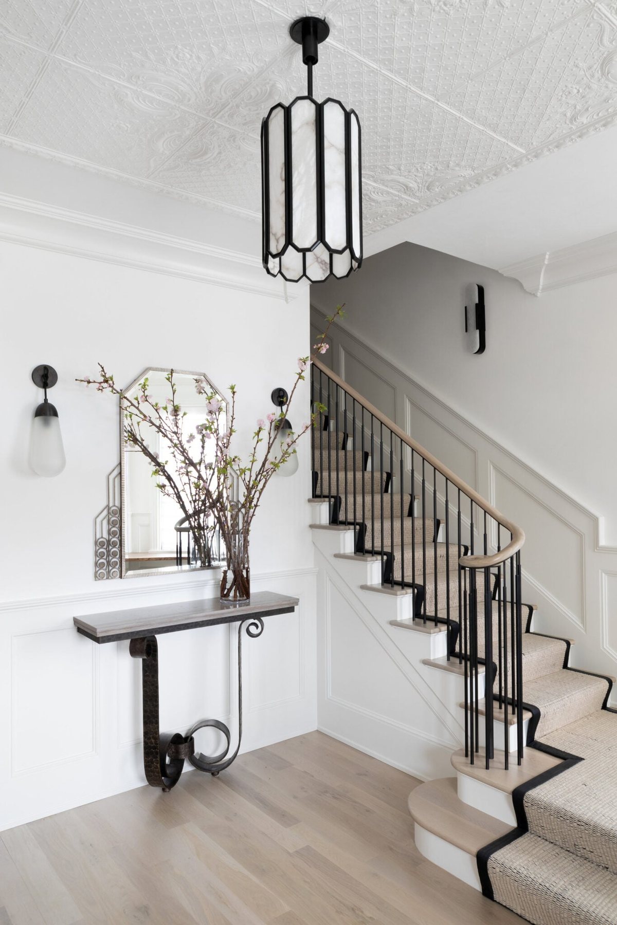 elegant entryway staircase with wood handrail and simple black balusters