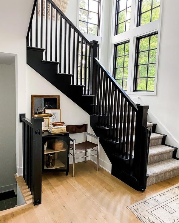black painted staircase with neutral striped rug