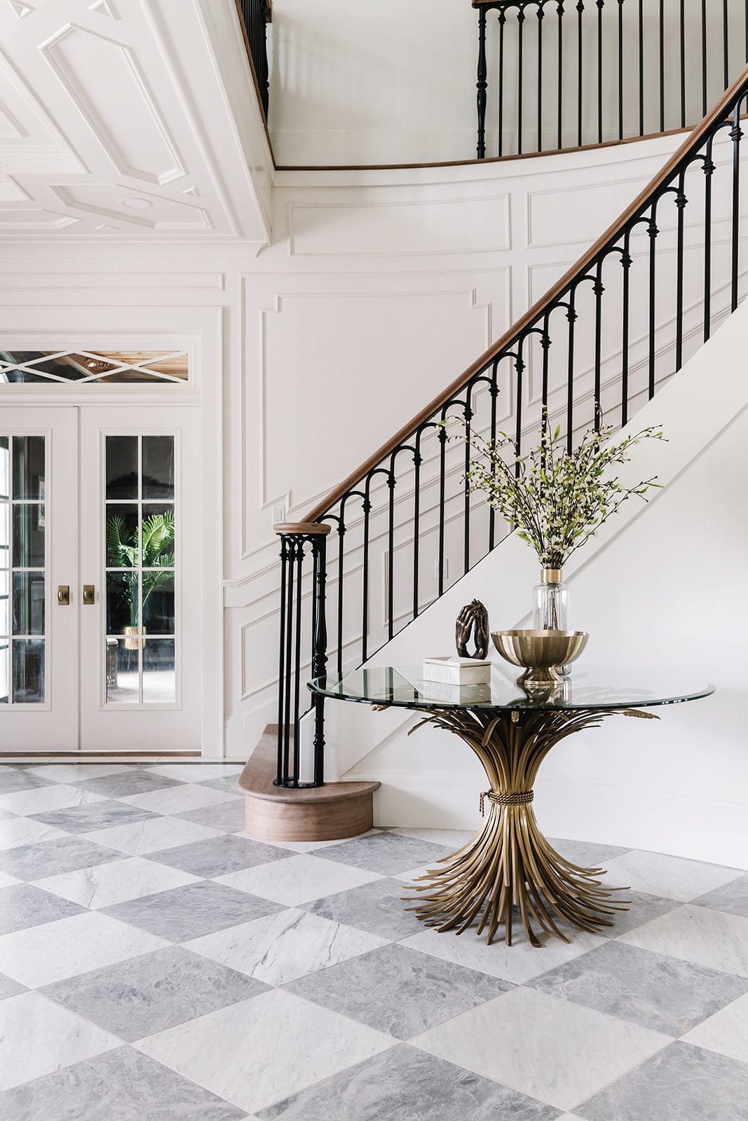 entryway staircase with wood handrail and black scalloped balusters