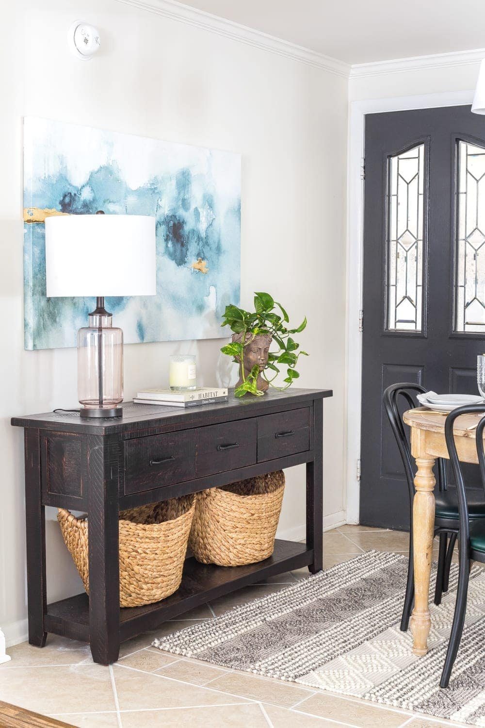 A console table beside an entry door in a breakfast nook to maximize on storage without the use of a mudroom.