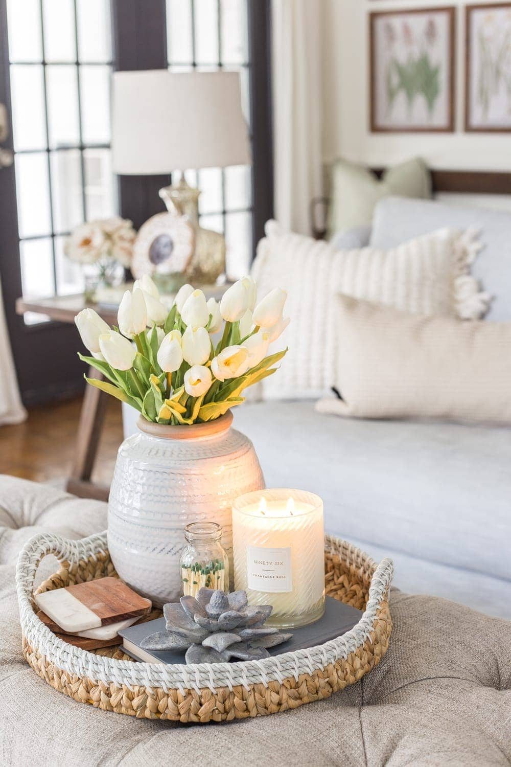 spring coffee table idea - vase of tulips, candle, concrete flower figurine, and basket tray