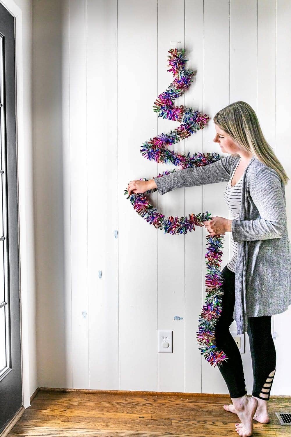hanging garland on wall hooks to make a DIY Christmas tree on a wall