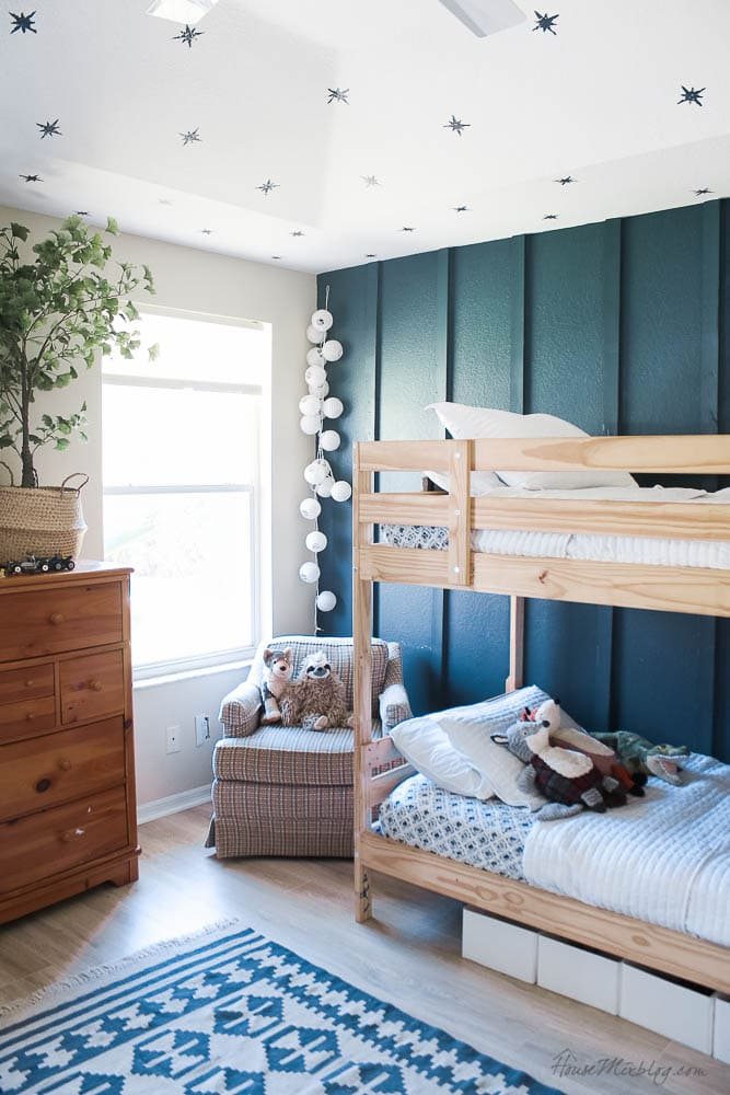 board and batten wall in a small bedroom with wallpaper ceiling