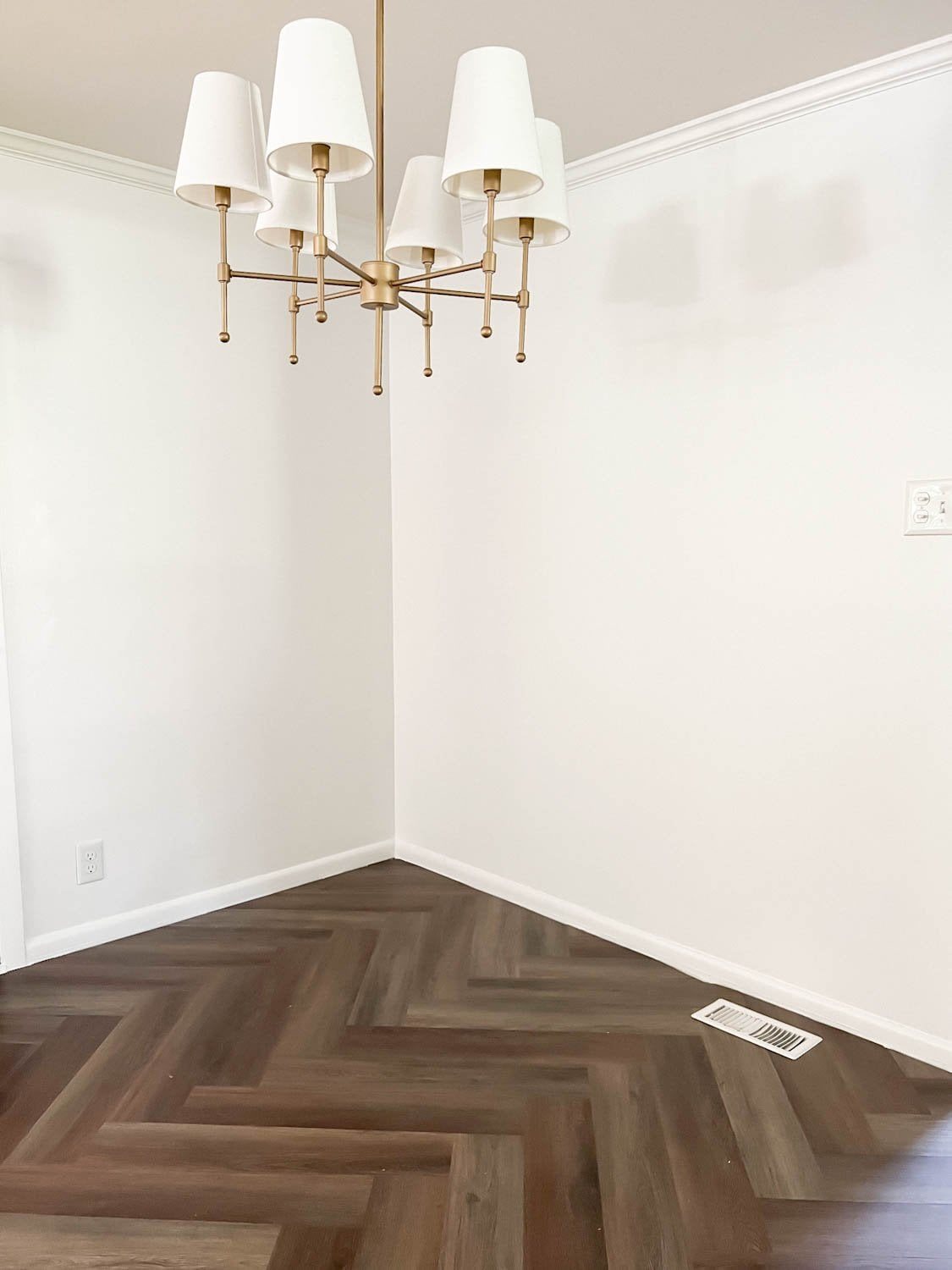 corner of breakfast nook with chandelier, white walls, and herringbone floor with a floor vent