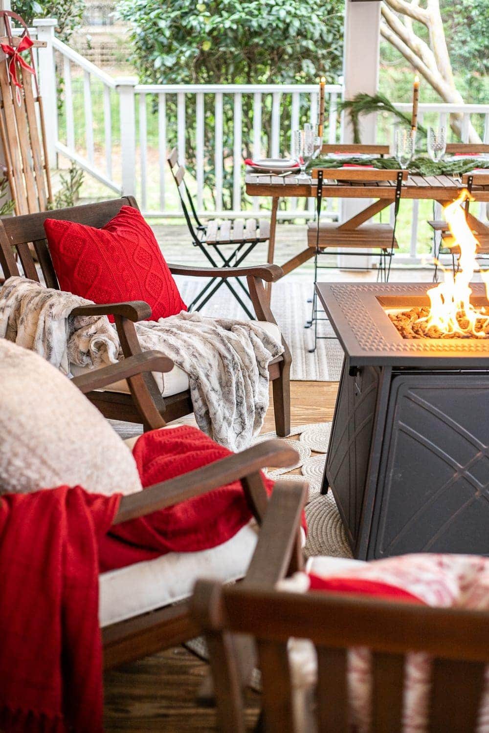 Cozy Christmas back porch with red blankets and pillows and a fire pit table